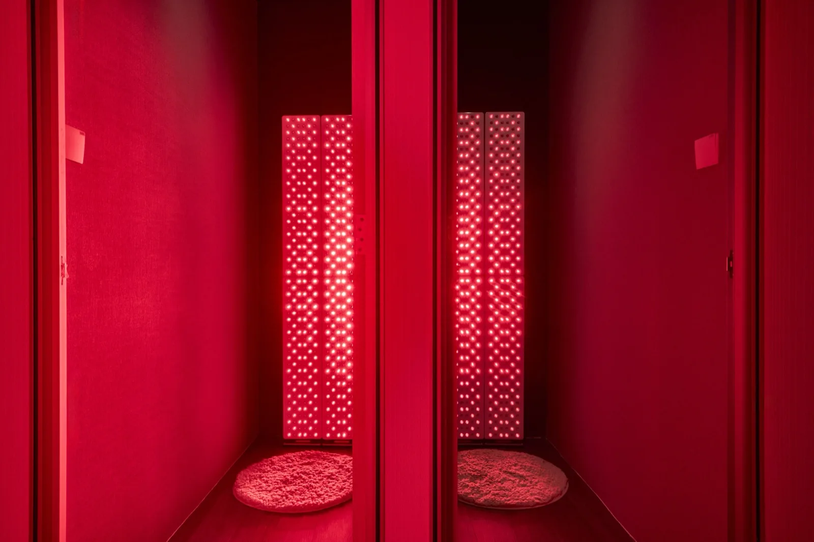 Full-body red light therapy panels glowing in a dark room.